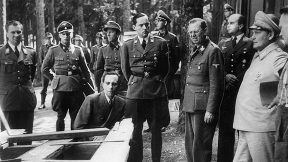 Joseph Goebbels, Hermann Göring und Hitlers Adjudant Schaub betrachten nach dem misslungenen Attentat 1944 zerstörte Möbelstücke. 