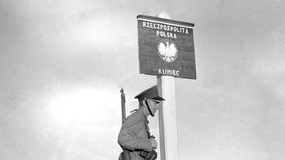 Ein polnischer Soldat steht 1939 neben einem Grenzschild auf dem Magyan Pass.