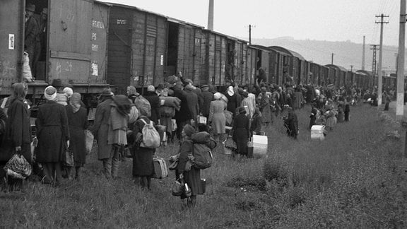 Archivaufnahme von Gruppe von Menschen, die einen Zug besteigen