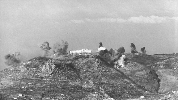 Historische Schwarweiß-Aufnahme: Bombeneinschläge auf einem Hügel