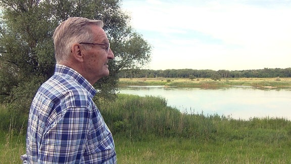 Ein älterer Mann blickt aufs Wasser.
