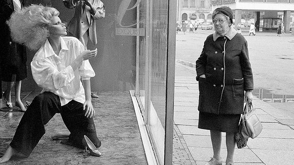 Eine Frau schaut in ein Schaufenster für Mode, in der DDR.