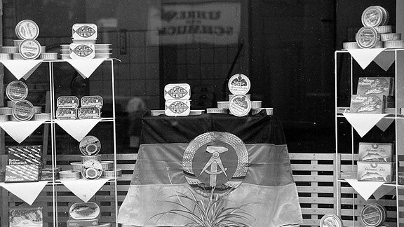Blick in ein Schaufenster mit Konserven, in der DDR.