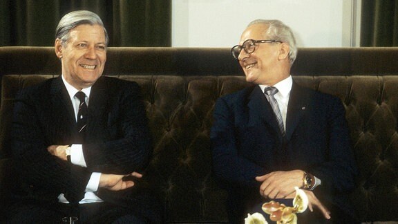 Bundeskanzler Helmut Schmidt sitzt neben Erich Honeckerauf einem Sofa.