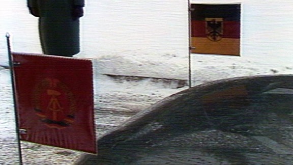 Blick auf Autokühlerhaube;links vorne ein DDR, rechts vorne ein BRD-Wimpel