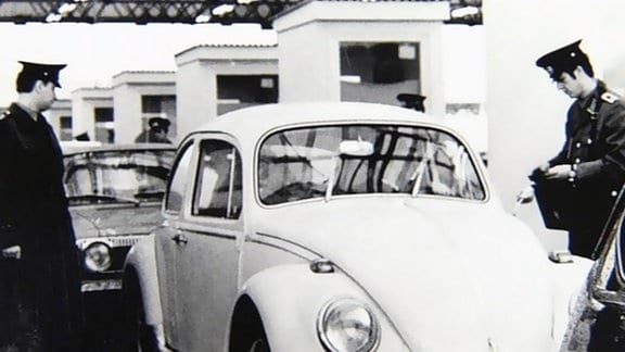 Zollbeamte kontrollieren einen VW Käfer bei der Einreise in die DDR