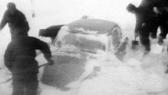 Ein eingeschneites Auto wird im Winter 1968 freigeschaufelt.