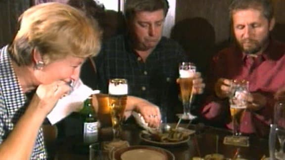 Leute an einem Tisch trinken Bier und essen Rollmops