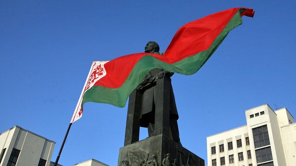 Die weißrussische Fahne vor einem Lenin-Denkmal
