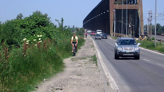 Ein Radfahrer fährt auf einem schotterigen, unbefestigten Seitenstreifen auf der Pancevo-Brücke in Belgrad.