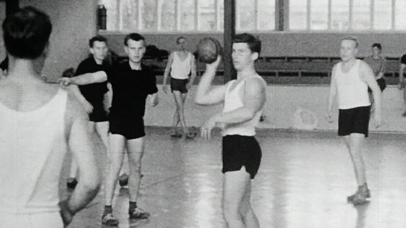Alte Schwarzweißaufnahme: Handballer in einer Turnhalle