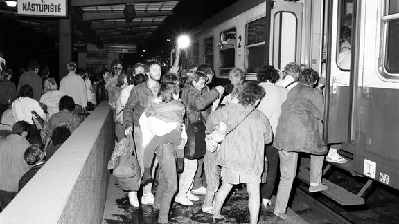 Ausreisewillige DDR-Bürger steigen 1989 auf dem Prager Bahnhof in einen bereitstehenden Zug.