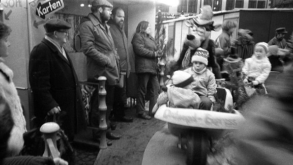 Kinder fahren Karrussel in den 80-er Jahren auf dem leipziger Weihnachtsmarkt.