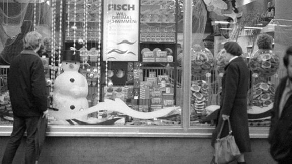 Leute stehen vor Schaufenster mit Schneemann in den 80-er Jahren in Leipzig.