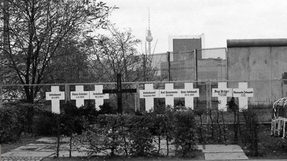 Berlin Mauerkreuze in der Nähe des Spreeufers am Reichstag erinnern an die Mauertoten. Fahrradfahrer vor dem im Boden eingelassenen Mauererinnerungsstreifen. 1982/2012