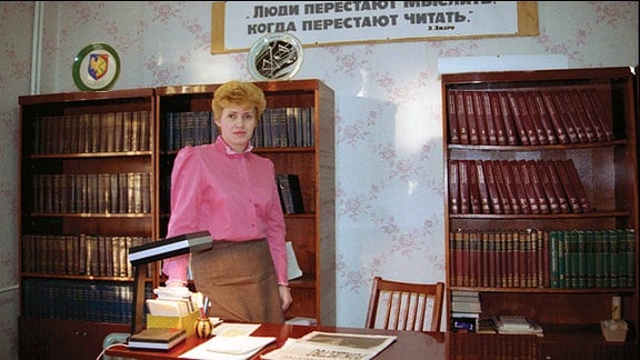 Eine Frau steht in einer Bibliothek.