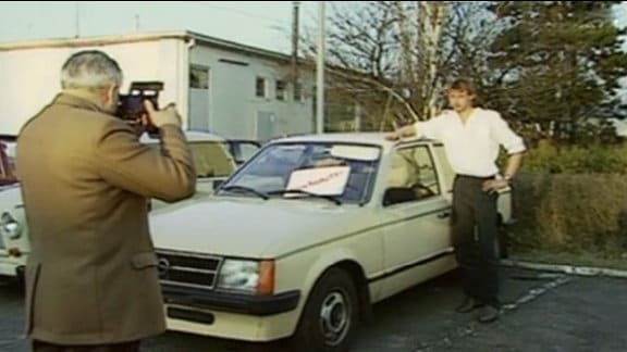 Ein junger Mann wird neben einem alten Opel Kadett fotografiert