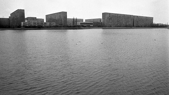 Blick über eine breite Wasserfläche auf ein Plattenbaugebiet