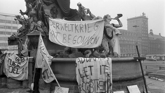 Der Leipziger Mendebrunnen hängt voller Protestplakate gegen den Krieg im Golf.