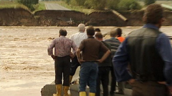 Männer stehen am Fluss.