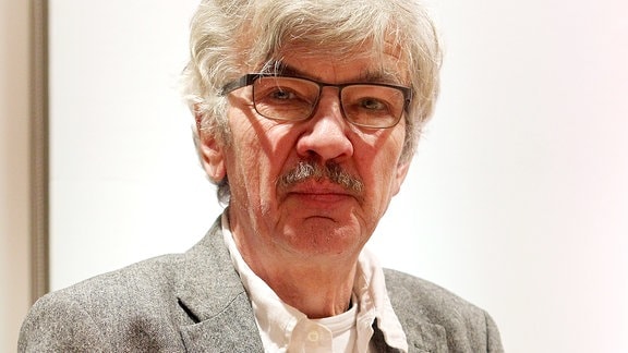 Schriftsteller Christoph Hein, ein Mann mit weißen Haaren, Brille, Schnauzbart und grauem Sakko 