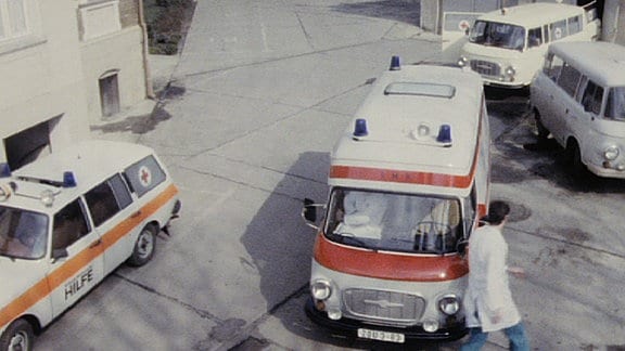 Blick aus Vogelpersepektive auf DDR-Krankenwagen mit Mediziner