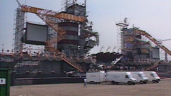 Drei weiße Transporter mit Anhängern vor dem Bühnenaufbauten des Stoneskonzerts  in Berlin Weißensee 1990