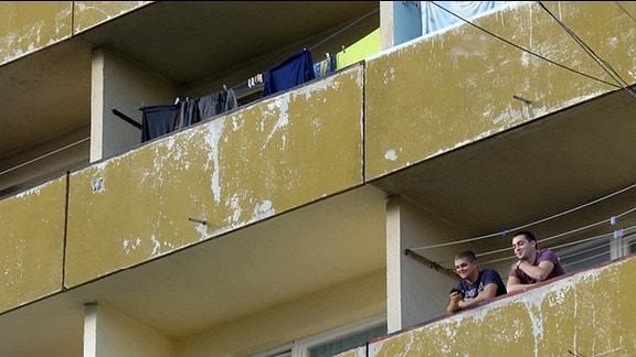 Nachaufnahme Plattenbau - zwei junge Männer auf einem Balkon.