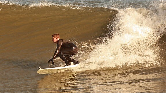 Ein Surfer steht auf einem Surfbrett
