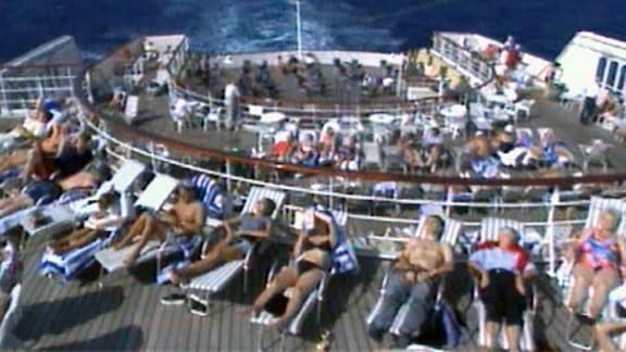 Passagiere sonnen sich auf einem Schiffsdeck