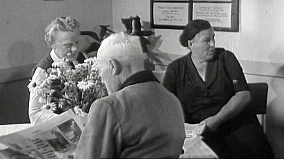 Senioren in einem Wartezimmer mit Blumen auf einem Tisch