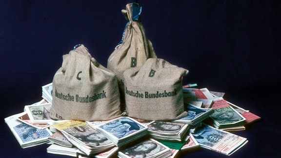 Säcke der Deutschen Bundesbank liegen auf einem Stapel alter D-Mark-Scheine.