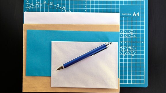 Briefumschläge und Kugelschreiber auf einer Schneideunterlage im A4 Format