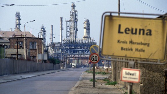 Ortsschild mit Blick auf das Gelände des VEB Leuna-Werke in Leuna/Sachsen-Anhalt, 1990