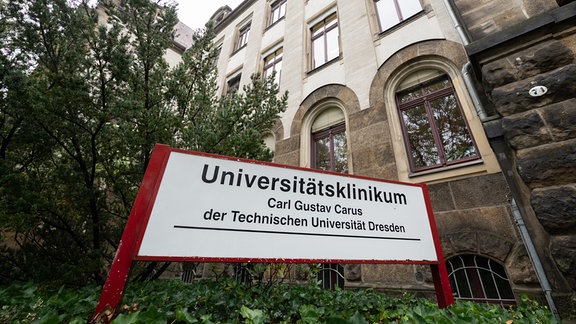 Ein Schild „Universitätsklinikum Carl Gustav Carus der Technischen Universität Dresden“ steht vor dem Vorstandsgebäude der Klinik.