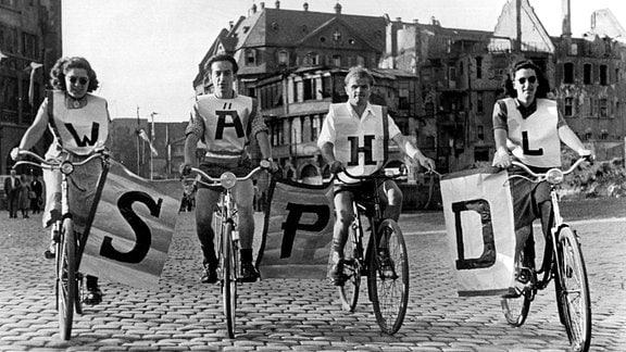 Mit selbstgebastelten Plakaten wirbt eine Gruppe Fahrradfahrer mit dem Slogan "Wähl SPD" für die Bundestagswahl 1949