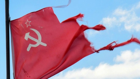 Eine zerfledderte Flagge der früheren Sowjetunion mit Hammer und Sicher auf rotem Grund flattert.