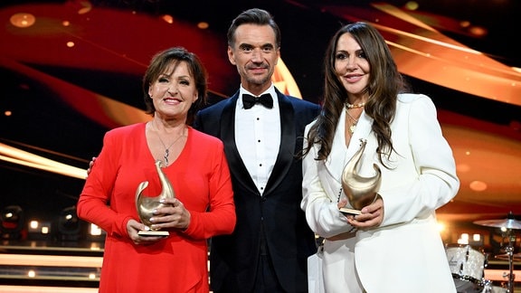 Ute Freudenberg und Simone Thomalla stehen nach der Verleihung des Medienpreises "Goldene Henne" mit ihren Trophäen neben Florian Silbereisen auf der Bühne.
