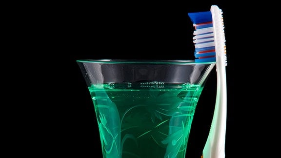 Ein Glas mit Mundwasser und eine Zahnbürste