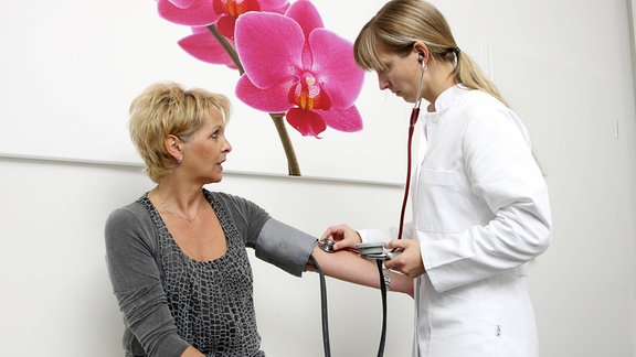 Sprechstundenhilfe misst den Blutdruck einer Patientin