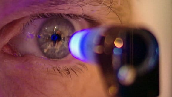 Ein Auge schaut auf ein blau leuchtendes Messgerät.