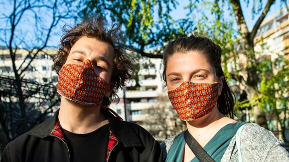 Paul und Laura tragen selbstgemachte bunte Mundschutzmasken in Berlin Kreuzberg am 6. April 2020.