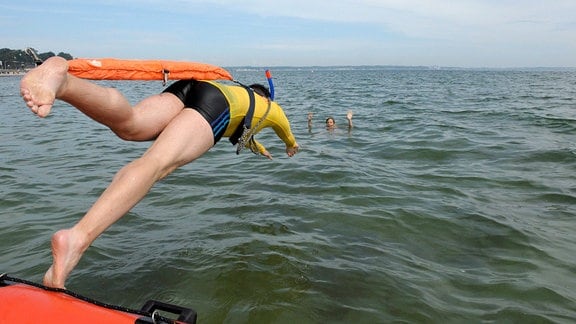Ein Rettungsschwimmer springt von einem Boot aus ins Wasser