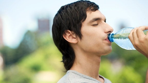 Ein junger Mann trinkt aus der Wasserflasche.