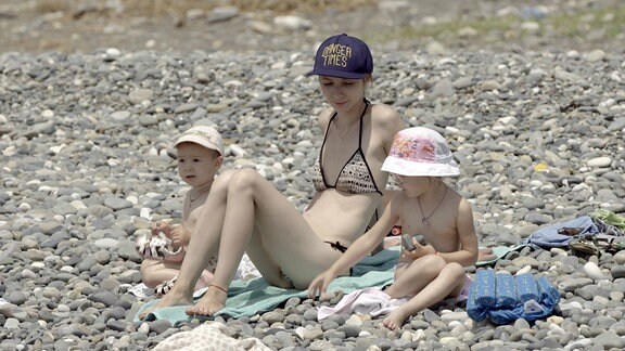 Frau im Bikini mit zwei Kindern am Strand