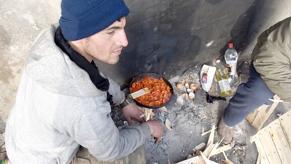 Belgrad, Flüchtlingslager: Junger Mann kocht Essen im Müll