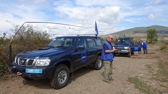 EUMM-Pressesprecher Hasso Resenbro vor zwei Geländewagen an der Adiminstrative Boundary Line (ABL) zwischen Georgien und Südossetien.