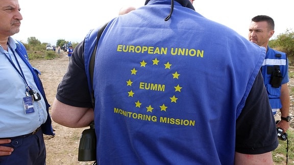 Rückseite einer blauen Weste mit der Emblem der European Monitoring Mission (EUMM).