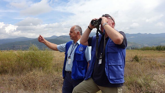 EUMM-Mitarbeiter Konstantinis Kondylis (links) und Hasso Resenbro (rechts) beobachten mit einer Feldstecher südossetisches Territorium. 