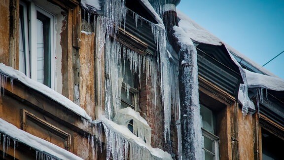 Eiszapfen hängen an einem Hausdach